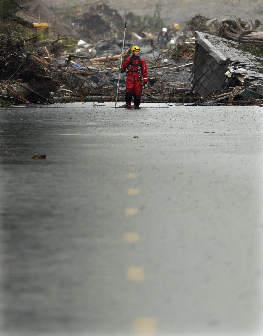 A search and rescue worker carrying a probe wades through water covering Washington Highway 530 Thursday, March 27, 2014, on the eastern edge of the massive mudslide that struck Saturday near Darrington, Wash. (AP Photo/Ted S. Warren, Pool)