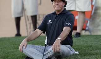 Phil Mickelson sits on the grass as watches his playing partners finish the 16th hole during the second round of the Texas Open golf tournament, Friday, March 28, 2014, in San Antonio. (AP Photo/Eric Gay)