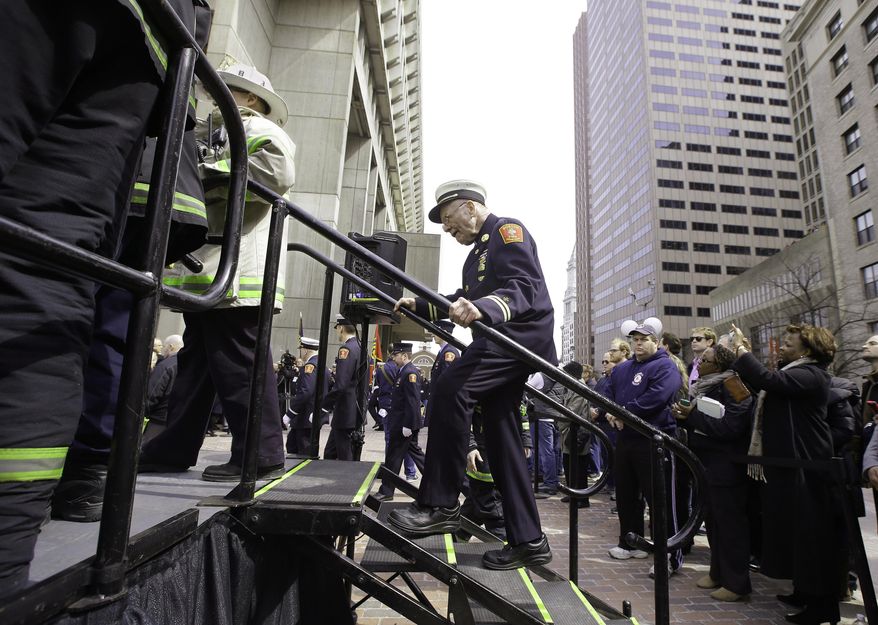 A member of the Boston Fire Department walks up the stage steps before a Boston Fire Department flag raising ceremony in honor of fallen firefighters Michael R. Kennedy and Lt. Edward J. Walsh on City Hall Plaza in Boston, Friday, March 28, 2014. Kennedy and Walsh were killed Wednesday, March 26, 2014 when they were trapped in the basement of a brownstone during a nine-alarm blaze. (AP Photo/Stephan Savoia)