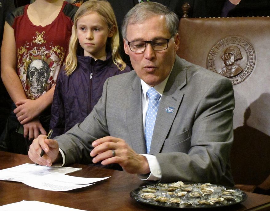 Washington Gov. Jay Inslee looks at a plate of Olympia oysters before signing a bill making the shellfish the official oyster of Washington state, Friday, March 28, 2014, in Olympia, Wash. The oysters are small and flat and found in low tide areas, mudflats and gravel bars in estuaries and bays. (AP Photo/Rachel La Corte)