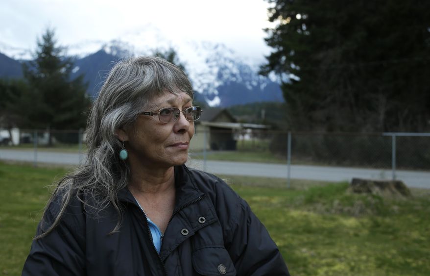Robin Youngblood poses for a photo Thursday, March 27, 2014, with Whitehorse Mountain behind her in Darrington, Wash. Youngblood survived the massive mudslide that hit the nearby community of Oso, Wash. last Saturday, and was rescued by a helicopter as she floated on a piece of a roof. (AP Photo/Ted S. Warren)