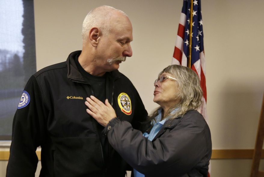 FILE - In this March 26, 2014 file photo, Robin Youngblood, right, smiles after embracing Snohomish County helicopter crew chief Randy Fay, who helped rescue her from the scene of a deadly mudslide days earlier, in Arlington, Wash. Youngblood was home when the mudslide hit, moving her house a quarter-mile where she was able to find her way out of the rubble. (AP Photo/Elaine Thompson, File)