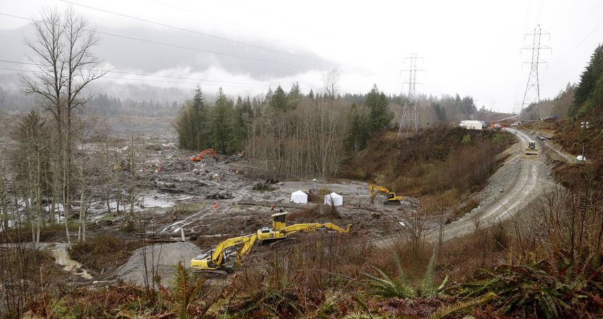A continues to be built at right to connect the two sides of the scene of a deadly mudslide to allow searchers though Saturday, March 29, 2014, in Oso, Wash. Besides the more than two dozen bodies already found, many more people could be buried in the debris pile left from the mudslide one week ago. Ninety people are listed as missing. (AP Photo/Elaine Thompson, Pool)