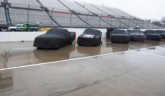 Trucks sit under covers as Air Titans try to keep the track dry during a rain delay at the  NASCAR Truck Series auto race at Martinsville Speedway in Martinsville, Va., Saturday, March 29, 2014. (AP Photo/Steve Sheppard)