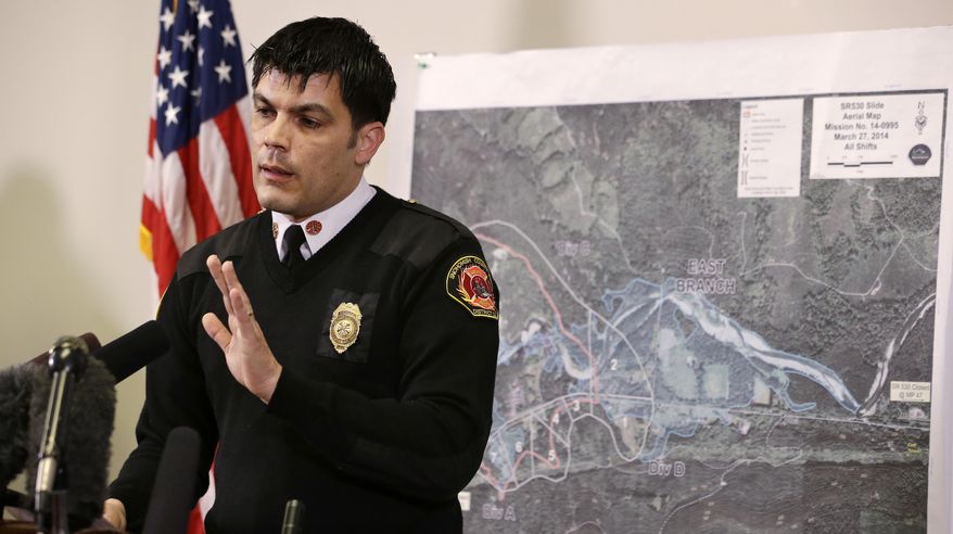With a map of the deadly mudslide behind him, Snohomish County District 21 Fire Chief Travis Hots addresses a news conference about progress in the search Friday, March 28, 2014, in Arlington, Wash. The death toll from the mudslide in nearby Oso, Wash., is expected to rise considerably within days as the Snohomish County Medical Examiner's Office catches up with the recovery effort, officials said. (AP Photo/Elaine Thompson)