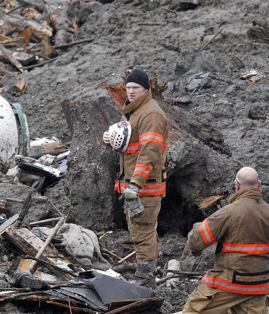 Searchers pause for a moment of silence at the scene of a deadly mudslide Saturday, March 29, 2014, in Oso, Wash. Besides the more than two dozen bodies already found, many more people could be buried in the debris pile left from the mudslide one week ago. Ninety people are listed as missing. (AP Photo/Elaine Thompson, Pool)