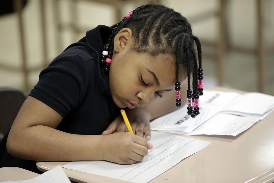 In this photo taken on Tuesday, March 25, 2013, Airia Turner, a second grader at George Buck Elementary School in Indianapolis, works on writing. The national math and education standards outlined in the Common Core are everywhere at Buck Elementary. Stapled packets of the standards hang outside classroom doors, and individual guidelines are cut out and displayed in the hallways next to hand-drawn graphs scribbled in crayon. A bill signed last Monday by Gov. Mike Pence makes Indiana the first state to revoke those standards, but what will replace them is unclear in a state where teachers are still reeling from years of change. (AP Photo/AJ Mast)