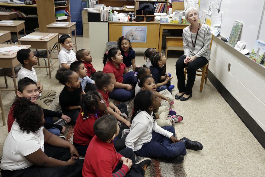 In this photo taken on Tuesday, March 25, 2013, Mrs. Mary Natali goes over some information on the dry-erase board with her first grade class at George Buck Elementary School in Indianapolis. The national math and education standards outlined in the Common Core are everywhere at Buck Elementary. Stapled packets of the standards hang outside classroom doors, and individual guidelines are cut out and displayed in the hallways next to hand-drawn graphs scribbled in crayon. A bill signed last Monday by Gov. Mike Pence makes Indiana the first state to revoke those standards, but what will replace them is unclear in a state where teachers are still reeling from years of change. (AP Photo/AJ Mast)