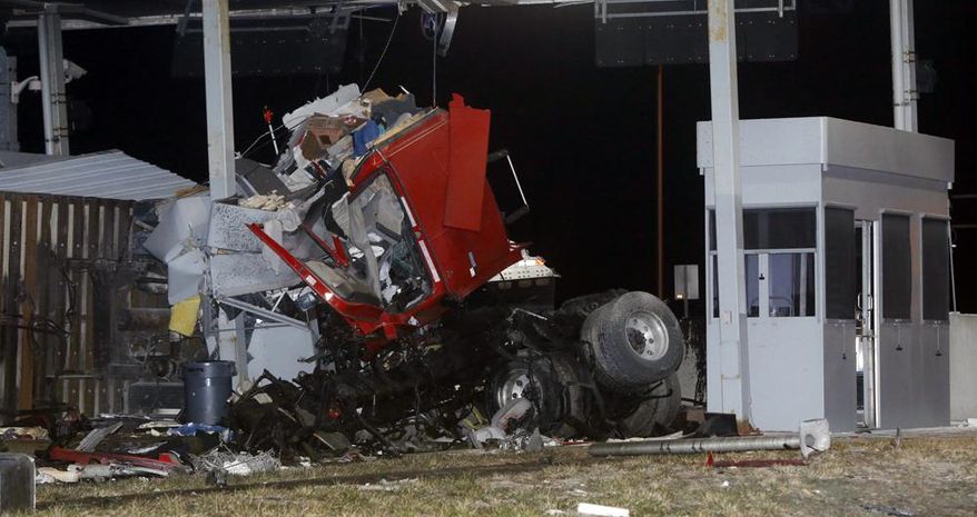 Debris is scattered after a tractor-trailer and a truck crashed into a Kansas Turnpike tollbooth on westbound Interstate 70 on Saturday, March 29, 2014. The Kansas Highway Patrol reports two men were in the truck that hit the tollbooth at highway speeds, never slowing down before crashing. The truck’s cab is wrapped around the tollbooth and the engine landed about 50 yards from the tollbooth. The patrol doesn’t know whether the driver or a passenger died in the crash. The tollbooths are unmanned at night. No one was in the booth at the time of the crash, the patrol said. (AP Photo/The Lawrence Journal-World, Richard Gwin)