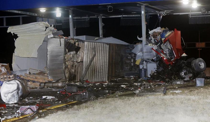 Debris is scattered after a tractor-trailer and a truck crashed into a Kansas Turnpike tollbooth on westbound Interstate 70 on Saturday, March 29, 2014. The Kansas Highway Patrol reports two men were in the truck that hit the tollbooth at highway speeds, never slowing down before crashing. The truck’s cab is wrapped around the tollbooth and the engine landed about 50 yards from the tollbooth. The patrol doesn’t know whether the driver or a passenger died in the crash. The tollbooths are unmanned at night. No one was in the booth at the time of the crash, the patrol said. (AP Photo/The Lawrence Journal-World, Richard Gwin)