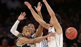 Michigan State&#39;s Adreian Payne passes the ball around Virginia&#39;s Anthony Gill during the second half of a regional semifinal at the NCAA men&#39;s college basketball tournament, Friday, March 28, 2014, in New York. (AP Photo/Seth Wenig)