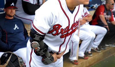 Atlanta Braves pitcher Kris Medlen wears an elbow brace on his right arm after season-ending Tommy John surgery as he waits during a rain delay in their exhibition baseball game against the team&#39;s minor league Future Stars Saturday, March 29, 2014, in Rome, Ga. (AP Photo/David Tulis)
