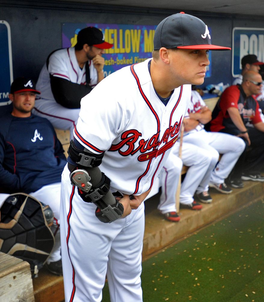 Atlanta Braves pitcher Kris Medlen wears an elbow brace on his right arm after season-ending Tommy John surgery as he waits during a rain delay in their exhibition baseball game against the team&#39;s minor league Future Stars Saturday, March 29, 2014, in Rome, Ga. (AP Photo/David Tulis)