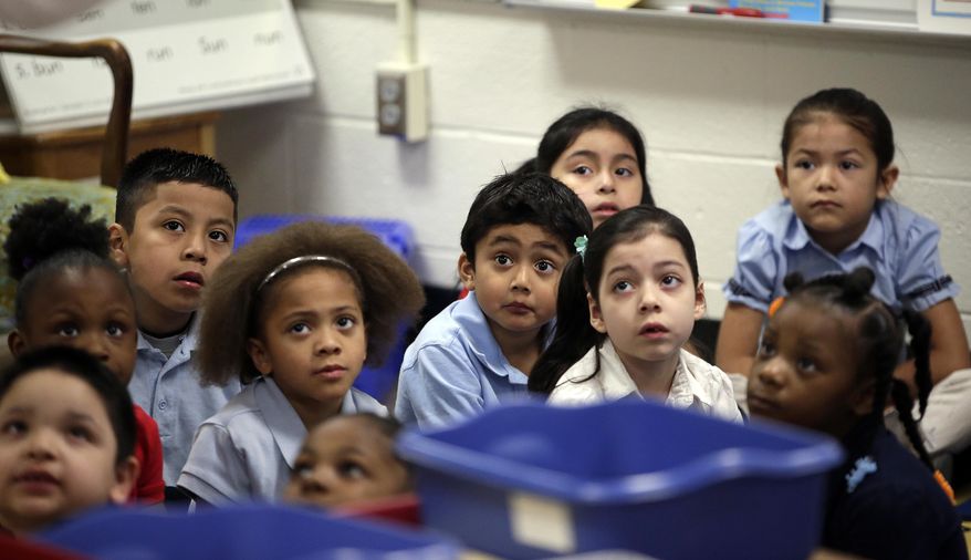 In this photo taken on Tuesday, March 25, 2013, kindergarteners listen as their teacher explains the day's activities to them at George Buck Elementary School in Indianapolis. The national math and education standards outlined in the Common Core are everywhere at Buck Elementary. Stapled packets of the standards hang outside classroom doors, and individual guidelines are cut out and displayed in the hallways next to hand-drawn graphs scribbled in crayon. A bill signed last Monday by Gov. Mike Pence makes Indiana the first state to revoke those standards, but what will replace them is unclear in a state where teachers are still reeling from years of change. (AP Photo/AJ Mast)