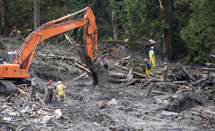 Searchers work at the scene of a deadly mudslide Saturday, March 29, 2014, in Oso, Wash. Besides the more than two dozen bodies already found, many more people could be buried in the debris pile left from the mudslide one week ago. Ninety people are listed as missing. (AP Photo/Elaine Thompson, Pool)