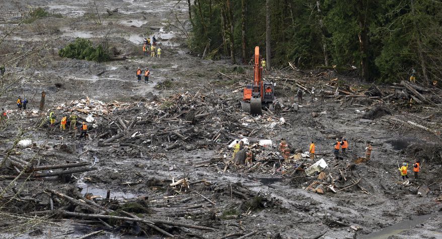Workers stand across a small portion of the scene of a deadly mudslide for a moment of silence Saturday, March 29, 2014, in Oso, Wash. Besides the more than two dozen bodies already found, many more people could be buried in the debris pile left from the mudslide one week ago. Ninety people are listed as missing. (AP Photo/Elaine Thompson, Pool)
