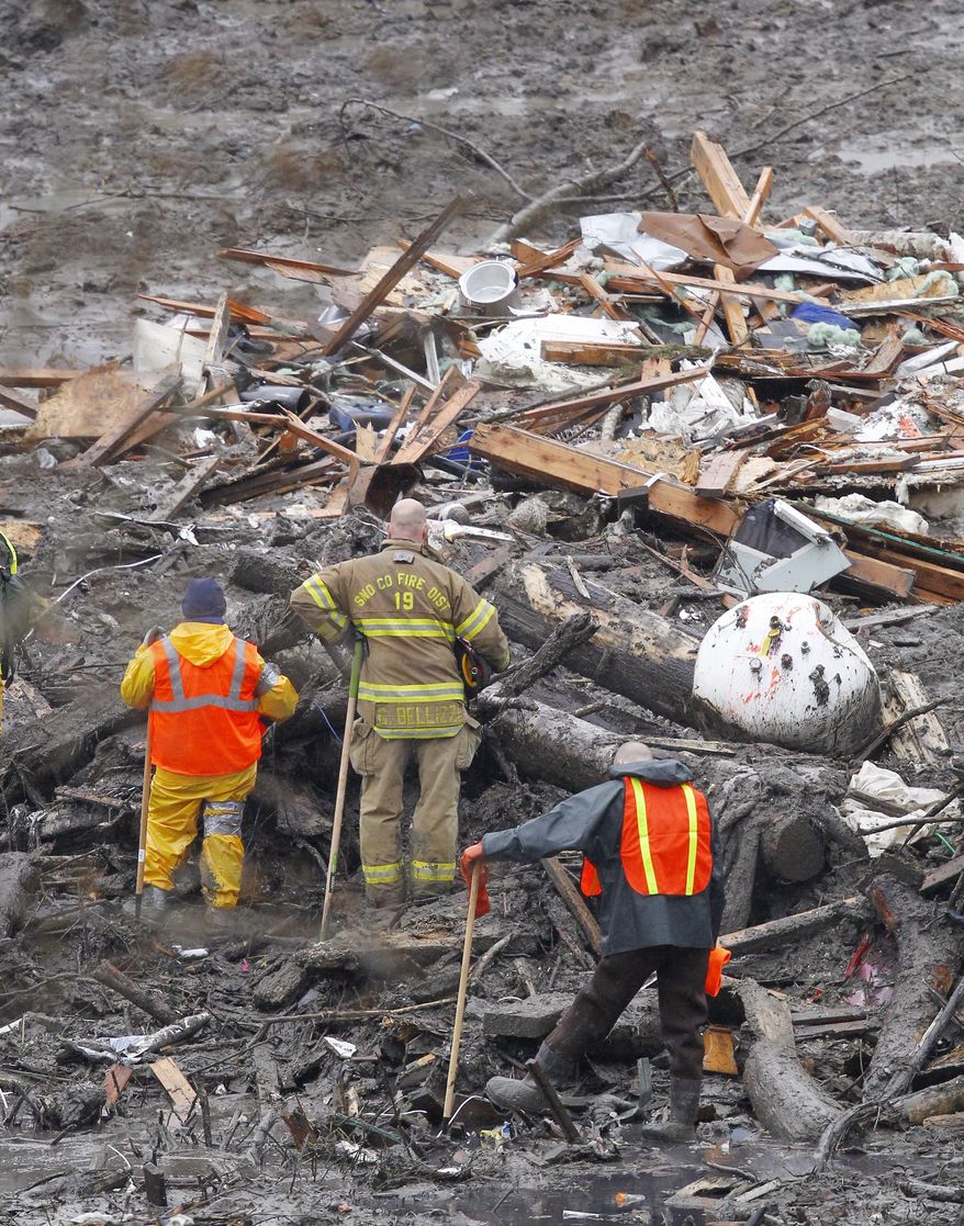 Searchers pause for a moment of silence at the scene of a deadly mudslide Saturday, March 29, 2014, in Oso, Wash. Besides the more than two dozen bodies already found, many more people could be buried in the debris pile left from the mudslide one week ago. Ninety people are listed as missing. (AP Photo/Elaine Thompson, Pool)