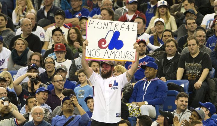 Fans wear Montreal Expos uniforms as they watch the Toronto Blue Jays in a preseason baseball game against the New York Mets on Friday, March 28, 2014, in Montreal. (AP Photo/The Canadian Press, Ryan Remiorz) **FILE**