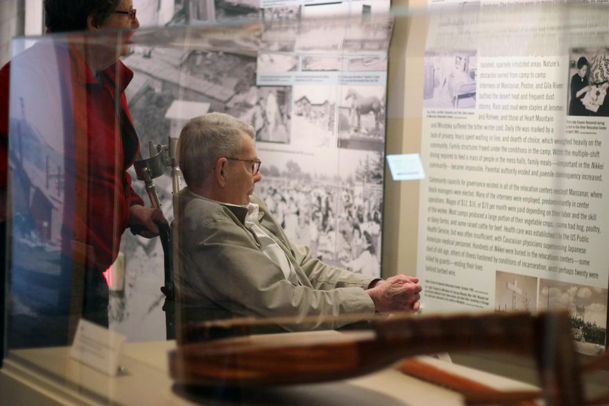 In this March 26, 2014 photo, Nancy and Charles Hardy read about the experience of Japanese-Americans sent to internment camps during World War II as they enter an exhibit titled “Barbed Wire to Battlefields” at the National World War II Museum in New Orleans. (AP Photo/Janet McConnaughey)
