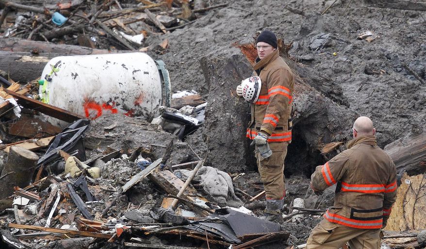 Searchers pause for a moment of silence at the scene of a deadly mudslide Saturday, March 29, 2014, in Oso, Wash. Besides the more than two dozen bodies already found, many more people could be buried in the debris pile left from the mudslide one week ago. Ninety people are listed as missing. (AP Photo/Elaine Thompson, Pool)