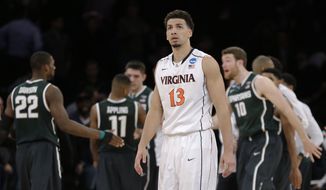 Virginia&#39;s Anthony Gill leaves the court as Michigan State players celebrate a 61-59 win over Virginia in a regional semifinal of the NCAA men&#39;s college basketball tournament, Saturday, March 29, 2014, in New York. (AP Photo/Seth Wenig)