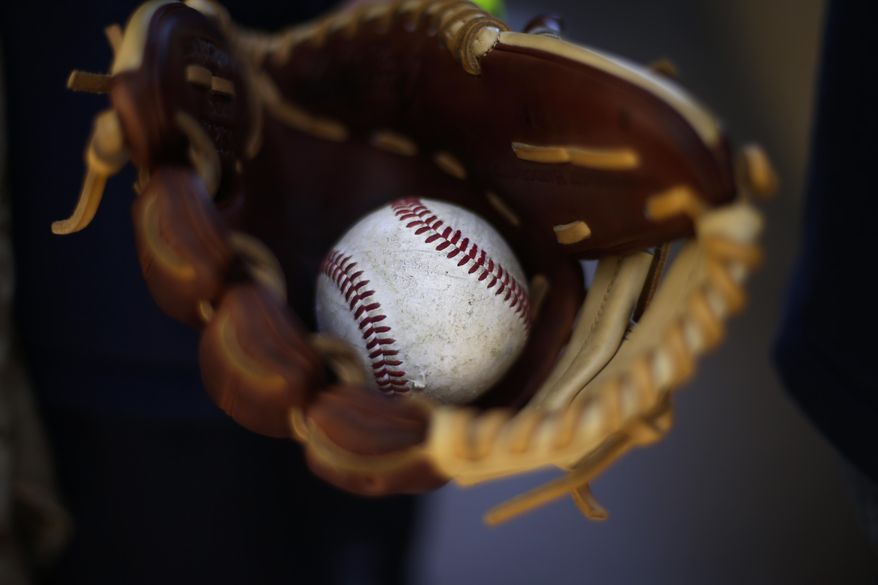 Peyton Berroth carries a baseball in his glove as he arrives to Petco Stadium before an opening day baseball game between the Los Angeles Dodgers and the San Diego Padres on Sunday, March 30, 2014, in San Diego. (AP Photo/Gregory Bull)