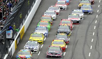 Driver Kyle Busch (18) leads the field to the green flag for the start of a NASCAR Sprint Cup Series auto race at Martinsville Speedway, Sunday, March 30, 2014, in Martinsville, Va. (AP Photo/Mike McCarn)