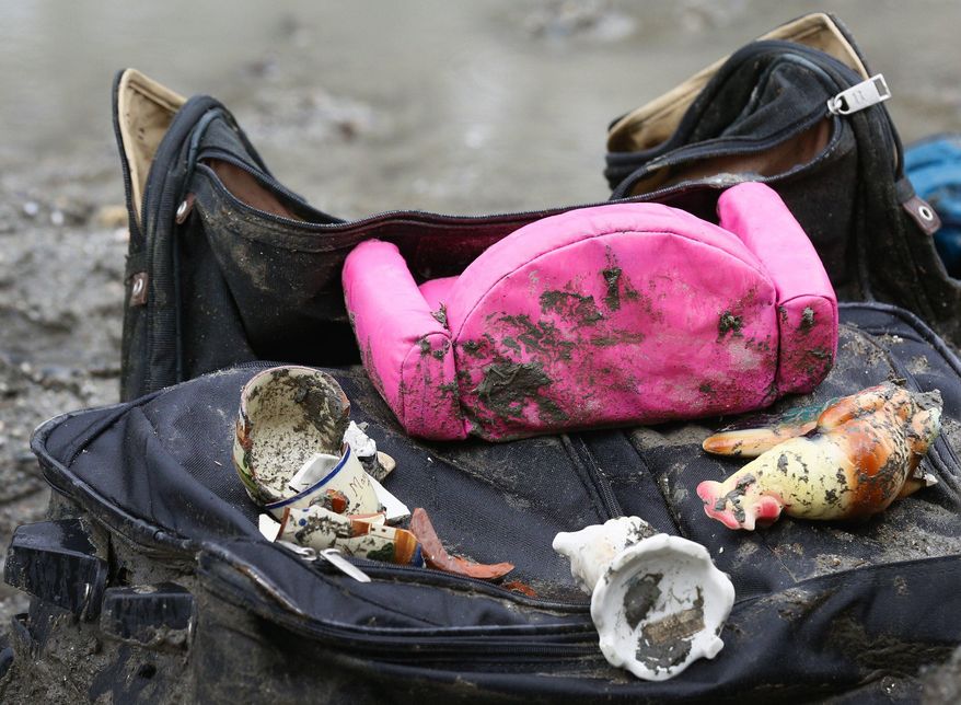 Assorted broken debris sits on a muddy suitcase pulled from the scene at the west side of the mudslide on Highway 530 near mile marker 37 on Sunday, March 30, 2014. Periods of rain and wind have hampered efforts the past two days, with some rain showers continuing today. Last night, the confirmed fatalities list was updated to 18, with the number of those missing falling from 90 to 30. (AP Photo/Rick Wilking, Pool)