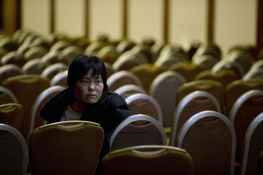 A woman, one of the relatives of Chinese passengers aboard the missing Malaysia Airlines flight MH370 sits alone after attending a briefing by Malaysian officials at a hotel in Beijing Sunday, March 30, 2014. Several dozen Chinese relatives of passengers on Flight 370 demanded Sunday that Malaysia apologize for its handling of the search for the missing plane and for the prime minister's statement saying it crashed into the southern Indian Ocean. (AP Photo/Andy Wong)