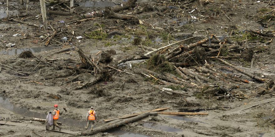 A worker carries a recovered item along a plywood walkway through other debris, Sunday, March 30, 2014, as search work continues at the site of the massive mudslide that struck the community of Oso,Wash. on March 22, 2014. (AP Photo/Ted S. Warren)