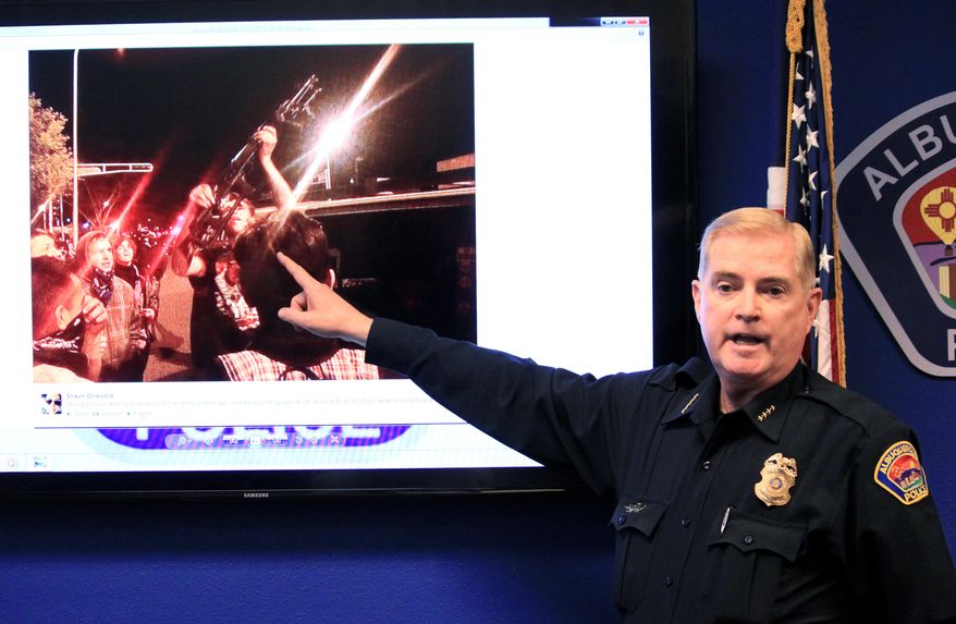 Albuquerque Police Chief Gorden Eden shows the image of a man who brought a rifle to an hours' long protest over police shootings during a news conference in Albuquerque, N.M. on Monday, March 31, 2014. Eden said the protest escalated and police were forced to use tear gas to keep what he described as a mob from hurting themselves, others and damaging property. (AP Photo/Susan Montoya Bryan)