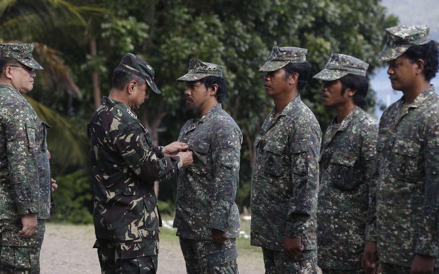 Philippine Western Command Chief Lt. Gen. Roy Deveraturda, pins a Bronze Cross medal on Marine 1st Lt. Mike Pelotera, Officer-in-Charge of a contingent which was deployed for five months on board the dilapidated navy ship LT57 BRP Sierra Madre off the disputed Second Thomas Shoal, locally known as Ayungin Shoal, on the South China Sea Monday March 31, 2014 in Palawan western Philippines. On Saturday, China Coast Guard attempted to block the Philippine government vessel AM700 carrying fresh troops to relieved the nine marines as well as supplies, but the latter successfully managed to dock beside the ship housing the troops. (AP Photo/Bullit Marquez)