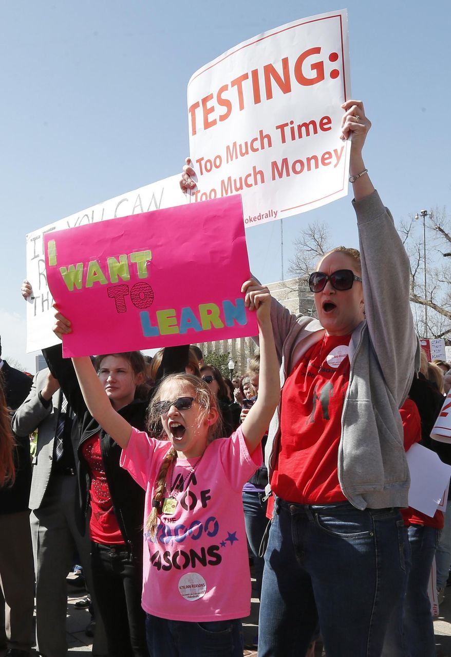 Ten-year-old Lexi Sendall, left, and Paula Sendall, right, of Choctaw, Okla., hold signs at a rally to call for an increase in school funding, which hasn't reached its pre-recession levels despite the addition of tens of thousands more students to the state's classrooms, in Oklahoma City, Monday, March 31, 2014. (AP Photo/Sue Ogrocki)