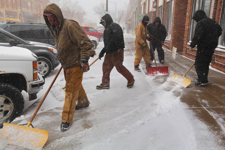 Employees with G.J. Holsworth & Sons shovel snow from the sidewalk in Rapid City, S.D., Monday, March 31, 2014. A spring snowstorm in the Upper Midwest on Monday shut down public schools, universities and government offices, made travel hazardous and life miserable for cattle ranchers in the midst of calving season. The National Weather Service issued blizzard warnings for much of the Dakotas and part of Minnesota, with the heaviest snow expected in eastern North Dakota and northwestern Minnesota. (AP Photo/Rapid City Journal, Benjamin Brayfield)