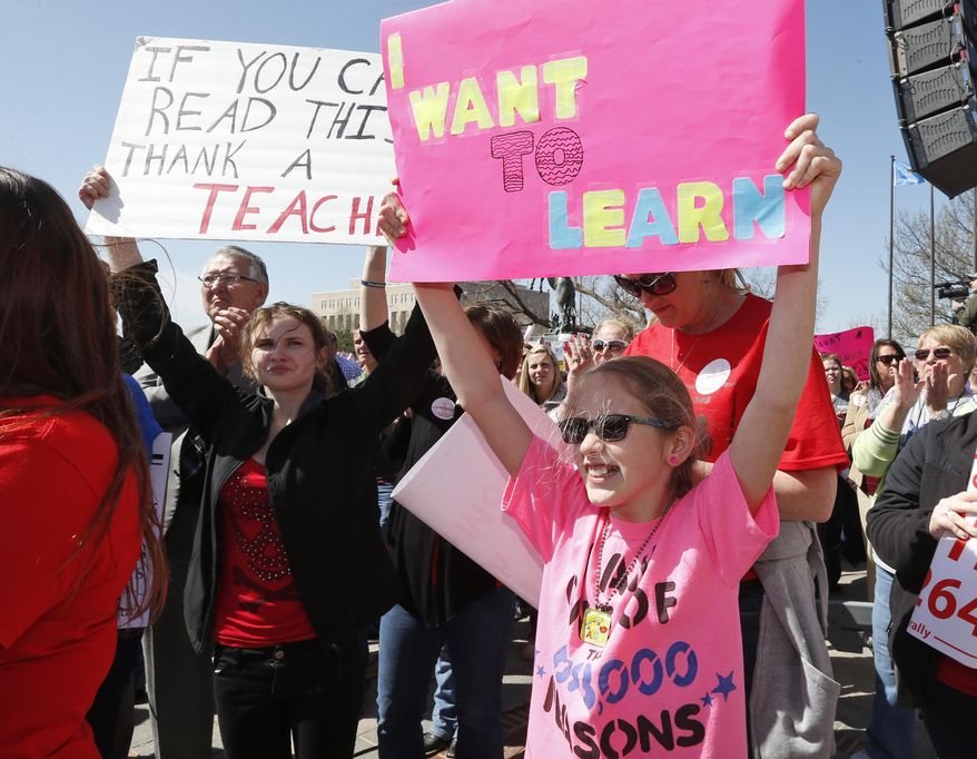 Emma Rose Kraus, left, a senior at Tulsa School of Art and Science, and ten-year-old Lexi Sendall, of Choctaw, Okla., hold signs at a rally to call for an increase in school funding, which hasn't reached its pre-recession levels despite the addition of tens of thousands more students to the state's classrooms, in Oklahoma City, Monday, March 31, 2014. (AP Photo/Sue Ogrocki)