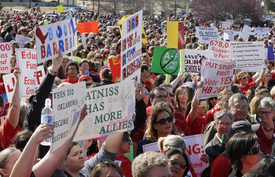 A variety of signs are held by people in the huge crowd of teachers, parents and children who amassed at the Oklahoma Capitol building in Oklahoma City, Monday, March 31, 2014, to call for an increase in school funding, which hasn't reached its pre-recession levels despite the addition of tens of thousands more students to the state's classrooms. (AP Photo/Sue Ogrocki)