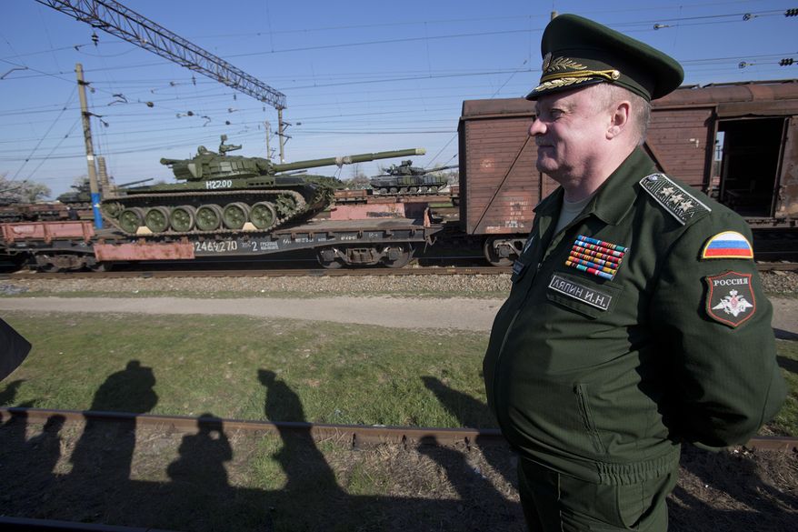 Russian head of Transport Department of the Ministry of Defense Colonel General Igor Lyapin smiles as Russian tanks T-72B, close left, arrive and Ukrainian tanks T-62, center back, are transported to the Ukraine at the Ostryakovo railway station not far from Simferopol, Crimea, Monday, March 31, 2014. (AP Photo/Pavel Golovkin)