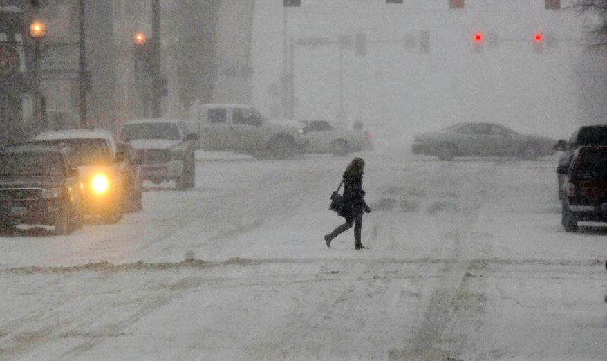 A pedestrian crosses the street in the snow, Monday, March 31, 2014, in Bismarck, N.D. Schools and universities across North Dakota are closing and no travel is advised in many areas because of a spring snow storm on Monday. (AP Photo/The Bismarck Tribune, Tom Stromme)