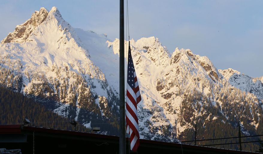 A U.S. flag hangs at half-staff with Whitehorse Mountain behind, during the early morning of Monday, March 31, 2014, at the fire station in Darrington, Wash. Crews have cleared a path through the muck and devastation wrought by Washington's deadly mudslide, making the painstaking search for victims easier. The makeshift road completed over the weekend links one side of the 300-acre debris field to the other. (AP Photo/Ted S. Warren)