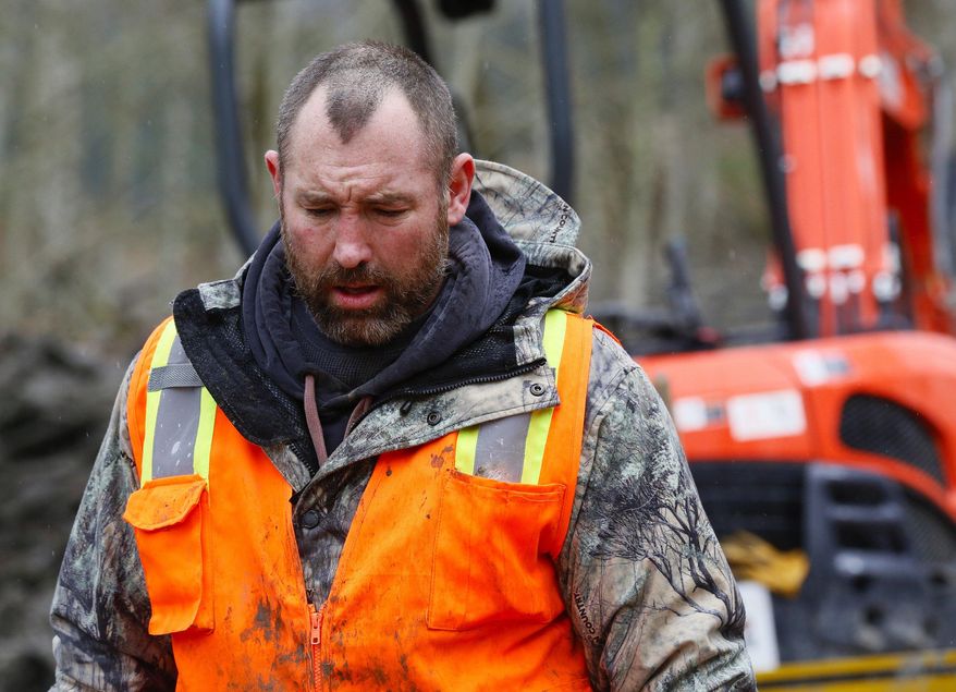 A weary searcher bows his head as he walks out of the west side of the mudslide site with a small saw on Highway 530 near mile marker 37 in Arlington, Wash., on Sunday, March 30, 2014. Periods of rain and wind have hampered efforts the past two days. (AP Photo/Rick Wilking, Pool)