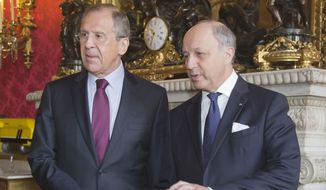Russian Foreign Minister Sergey Lavrov, left, and French Foreign Minister Laurent Fabius, right, shake hands in the lobby of the foreign ministry in Paris, Monday, March 31, 2014. Lavrov is in Paris for talks about Ukraine.  (AP Photo/Michel Euler)