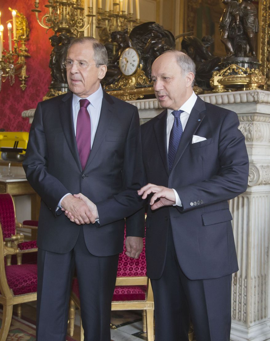 Russian Foreign Minister Sergey Lavrov, left, and French Foreign Minister Laurent Fabius, right, shake hands in the lobby of the foreign ministry in Paris, Monday, March 31, 2014. Lavrov is in Paris for talks about Ukraine. (AP Photo/Michel Euler)