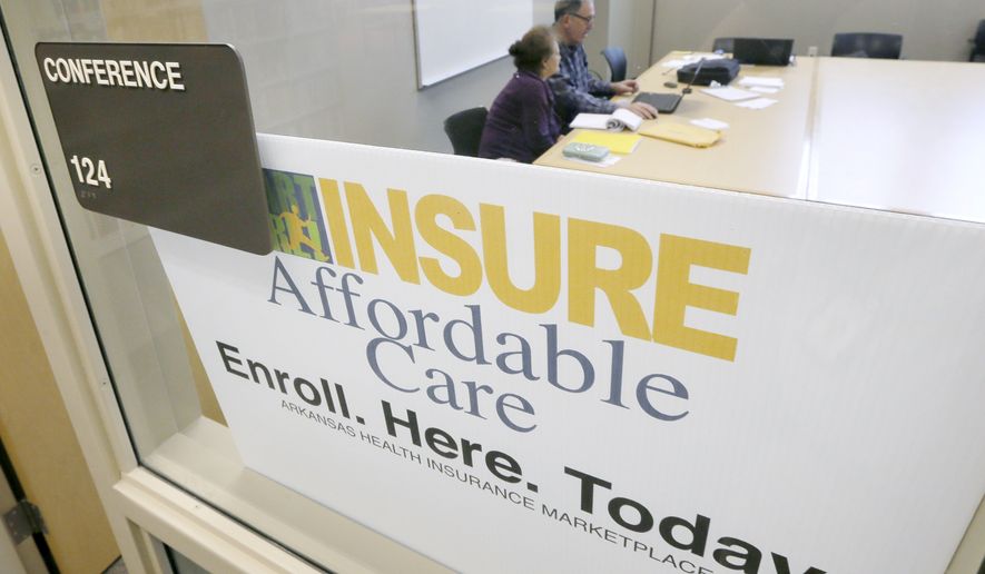**FILE** A man assists a woman sign up for health insurance at Laman Public Library in North Little Rock, Ark., Monday, March 31, 2014. Monday is the deadline to sign up for private heath insurance in the online markets created by President Obama's heath care law. (AP Photo/Danny Johnston)
