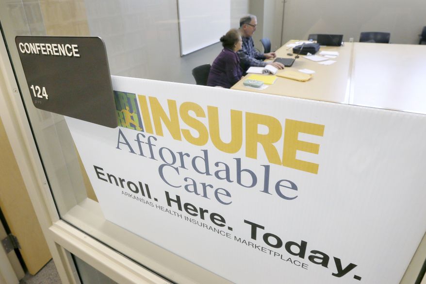 **FILE** A man assists a woman sign up for health insurance at Laman Public Library in North Little Rock, Ark., Monday, March 31, 2014. Monday is the deadline to sign up for private heath insurance in the online markets created by President Obama's heath care law. (AP Photo/Danny Johnston)