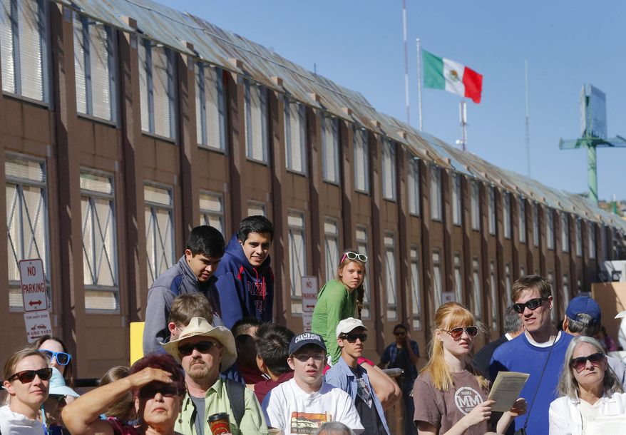 Hundreds gather to hear Boston Archdiocese Cardinal Sean O'Malley leads mass, Tuesday, April 1, 2014,along the international border wall in Nogales, Ariz. A delegation of Roman Catholic leaders celebrated Mass along the U.S.-Mexico border to raise awareness about immigration and to pray for policy changes. (AP Photo/Matt York)