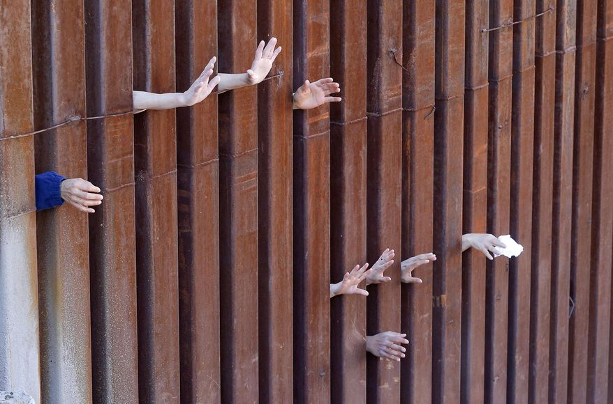 People on the Mexican side of the international border worship while Cardinal Sean O'Malley leads mass, Tuesday, April 1, 2014, in Nogales, Ariz. A delegation of Roman Catholic leaders celebrated Mass along the U.S.-Mexico border to raise awareness about immigration and to pray for policy changes. (AP Photo/Matt York)