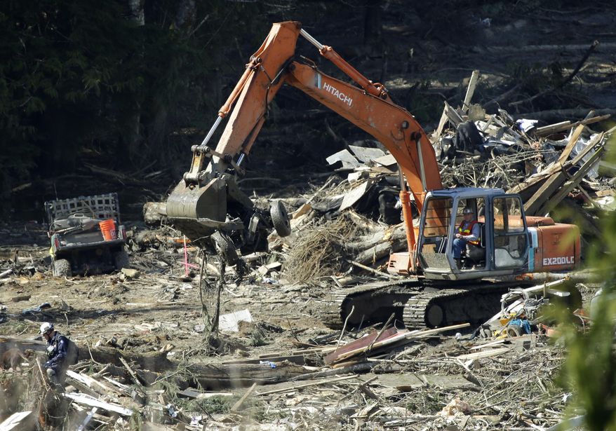 A piece of heavy equipment carries a mangled vehicle Tuesday, April 1, 2014, near Darrington, Wash., at the site of the deadly mudslide that hit the community of Oso,Wash. on March 22, 2014. Good weather and falling water levels aided the search for victims Tuesday. (AP Photo/Ted S. Warren)