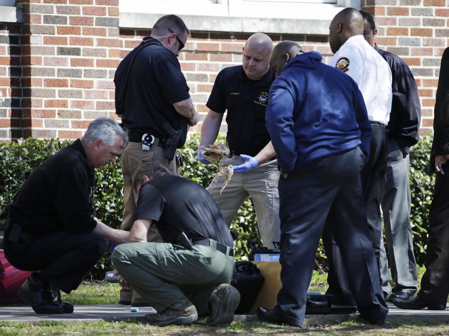 Authorities collect evidence while investigating a suspected incendiary device that was found outside Alonzo Crim Open Campus High School, Tuesday, April 1, 2014, in Atlanta. Atlanta Fire Rescue spokeswoman Janet Ward says authorities were called to a small fire outside the school Tuesday afternoon. Ward says the fire was extinguished before firefighters arrived and arson investigators are also on the scene. Local media outlets reported that authorities recovered a plastic bottle containing an undisclosed liquid. No injuries have been reported. (AP Photo/David Goldman)