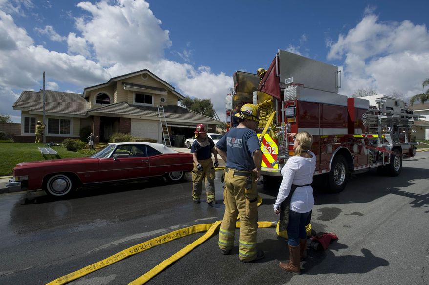 OCFA firefighters clean up after knocking down a house fire in Yorba Linda, Calif., Tuesday, April 1, 2014. Authorities say four people were injured in a Southern California house fire including two deputies and a 90-year-old woman they tried to rescue. (AP Photo/The Orange County Register, Joshua Sudock)