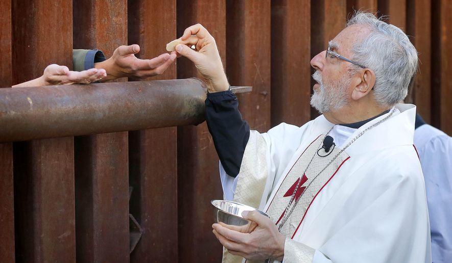 Most Reverend Gerald F. Kicanas, Bishop of Tucson, offers communion to people on the Mexican side of the international border, Tuesday, April 1, 2014, in Nogales, Ariz. Kicanas and Boston Archdiocese Cardinal Sean O'Malley, along with several Bishops who serve along the U.S./Mexico border, were visiting the border town to bring awareness to immigration reform and to remember those who have died trying to cross the border in years past. (AP Photo/Matt York)